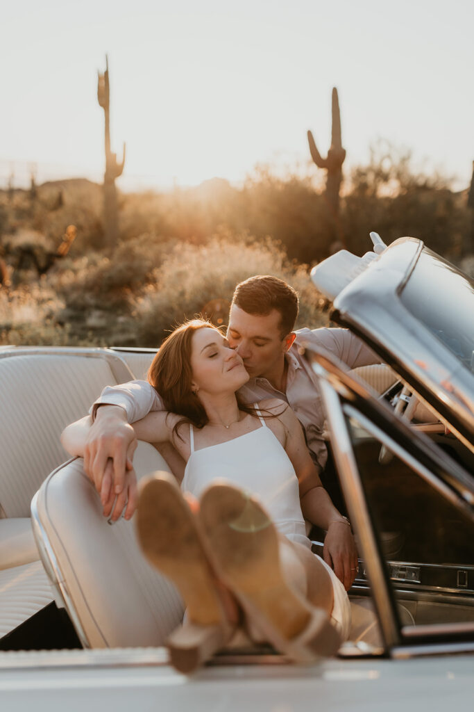 Couple sitting in a vintage car during golden hour in the desert