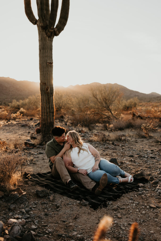 Couple sits on a blanket during golden hour in the desert.